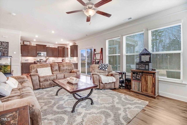 living room featuring light hardwood / wood-style flooring, ornamental molding, and ceiling fan