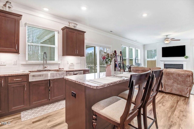 kitchen featuring sink, light hardwood / wood-style flooring, a kitchen breakfast bar, a center island, and tasteful backsplash