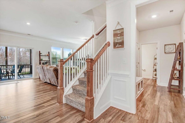 staircase featuring hardwood / wood-style floors and ornamental molding