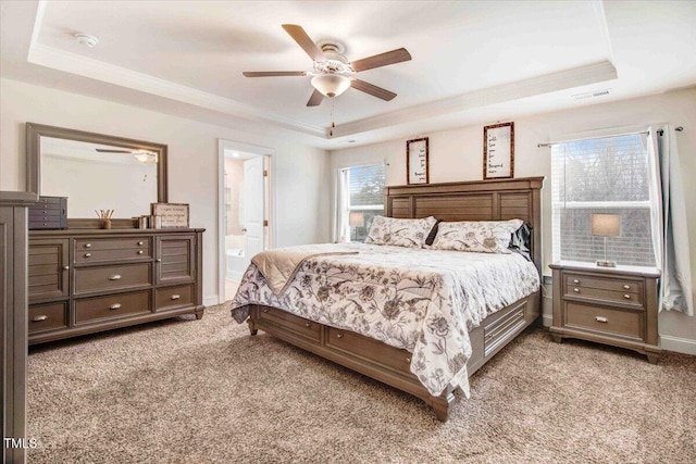 bedroom featuring ornamental molding, connected bathroom, light carpet, and a tray ceiling