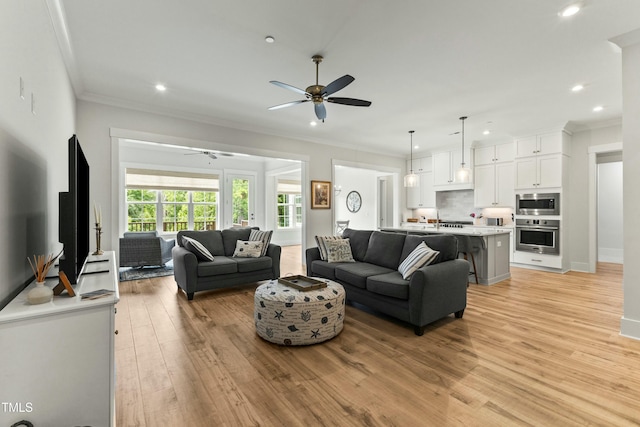 living room featuring crown molding, light hardwood / wood-style flooring, and ceiling fan