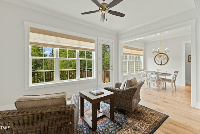 sunroom featuring ceiling fan with notable chandelier and a wealth of natural light