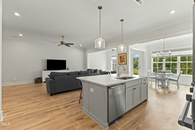 kitchen featuring pendant lighting, sink, light hardwood / wood-style flooring, dishwasher, and a center island with sink