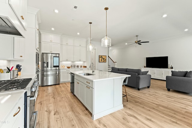 kitchen with sink, stainless steel appliances, white cabinets, and a center island with sink