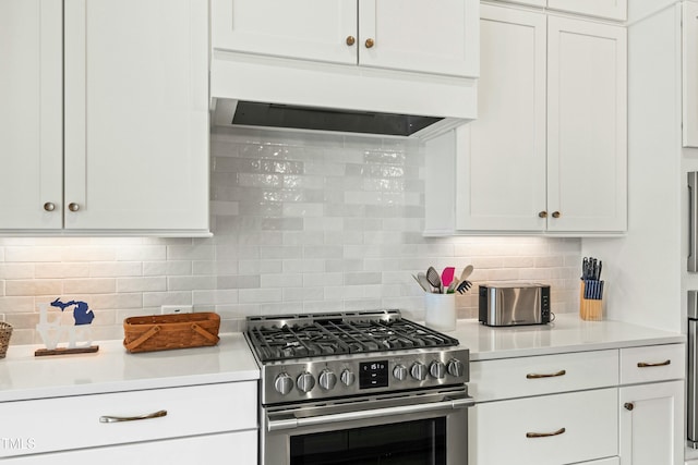 kitchen featuring backsplash, white cabinets, and stainless steel gas range oven