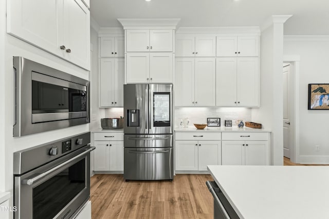 kitchen featuring white cabinetry, appliances with stainless steel finishes, crown molding, and decorative backsplash