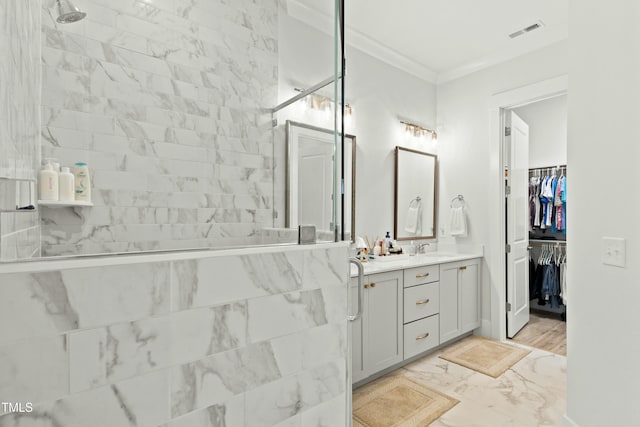 bathroom featuring crown molding, vanity, and a tile shower