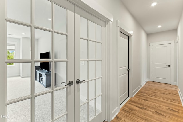 hallway with hardwood / wood-style flooring and french doors