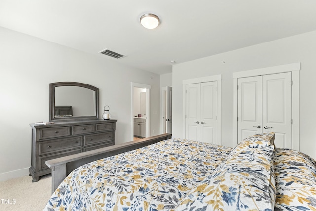 bedroom featuring light colored carpet and two closets