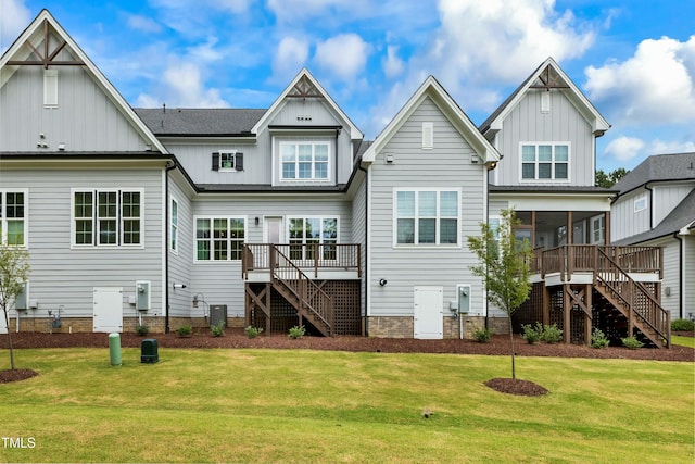 rear view of house with a sunroom, a deck, and a lawn