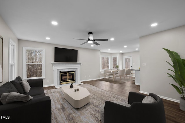 living room with ceiling fan, a fireplace, and dark hardwood / wood-style flooring