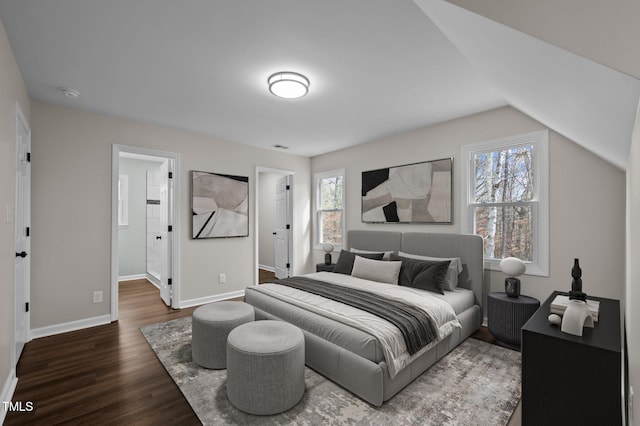 bedroom with dark wood-type flooring, ensuite bath, and lofted ceiling