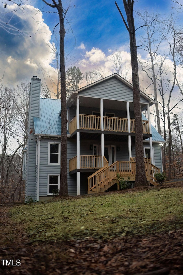 back of house featuring a balcony and a yard