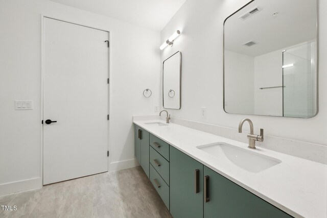 bathroom featuring a sink, visible vents, wood finished floors, and double vanity