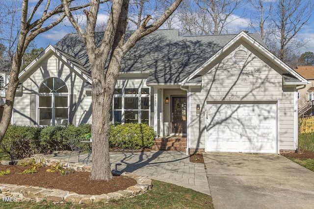 view of front of house with concrete driveway, a garage, and roof with shingles