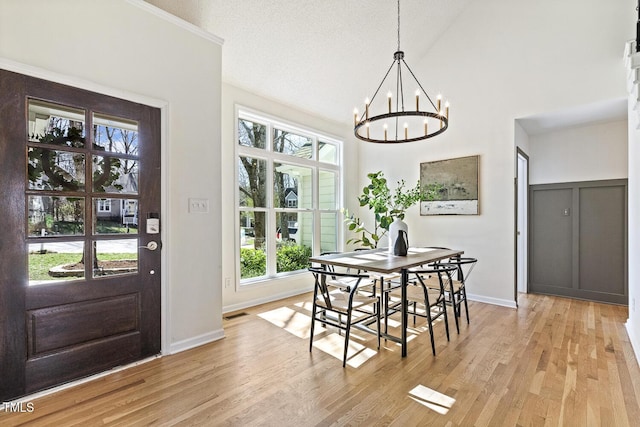 dining area with baseboards, light wood-style floors, a chandelier, and a textured ceiling