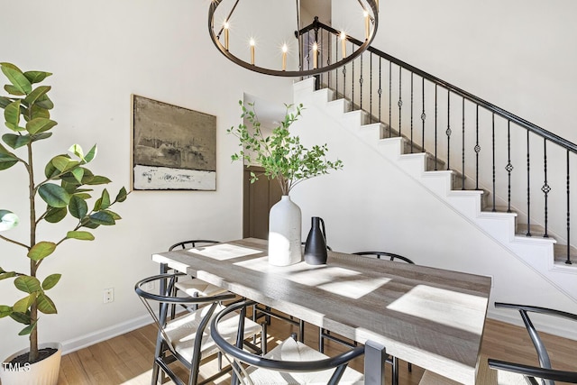 dining room with stairs, a notable chandelier, wood finished floors, and baseboards