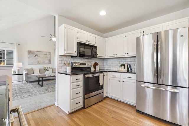 kitchen with dark countertops, decorative backsplash, stainless steel appliances, and light wood-style floors