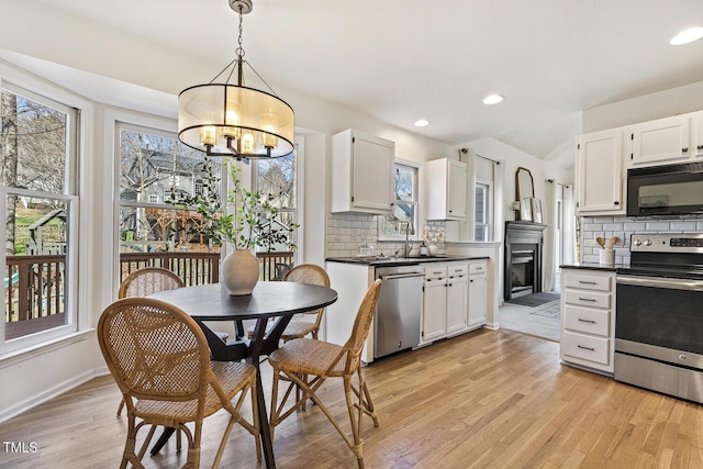 kitchen featuring stainless steel appliances, dark countertops, and light wood finished floors