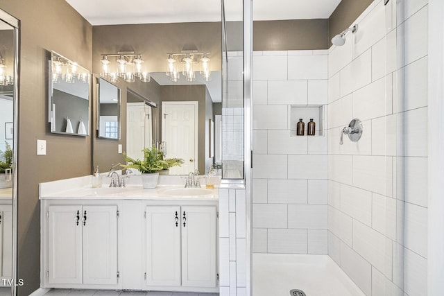 full bath with double vanity, tiled shower, and a sink