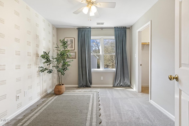 empty room with visible vents, baseboards, carpet, and a ceiling fan