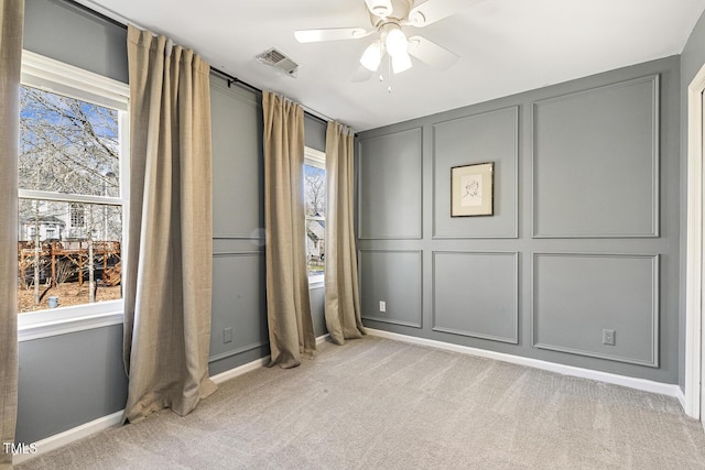 unfurnished bedroom with baseboards, light carpet, a ceiling fan, and a decorative wall