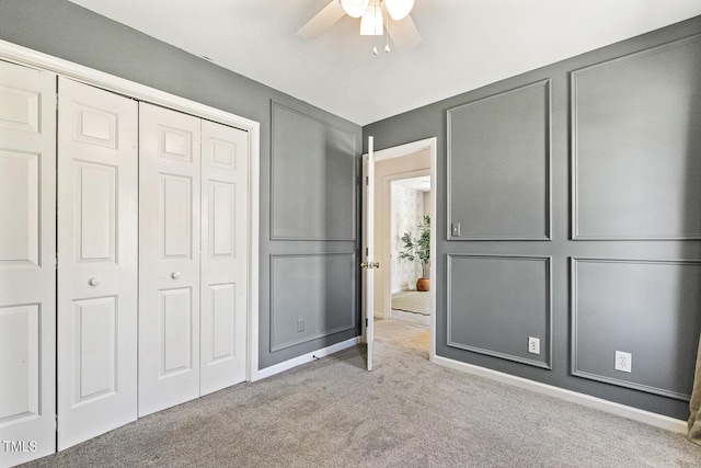 unfurnished bedroom with a decorative wall, carpet, a closet, and ceiling fan