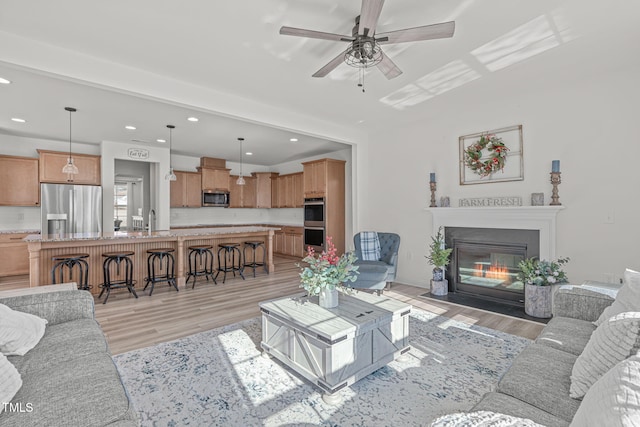 living room with sink, light hardwood / wood-style flooring, and ceiling fan