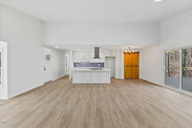 unfurnished living room with an inviting chandelier, high vaulted ceiling, light hardwood / wood-style floors, and sink