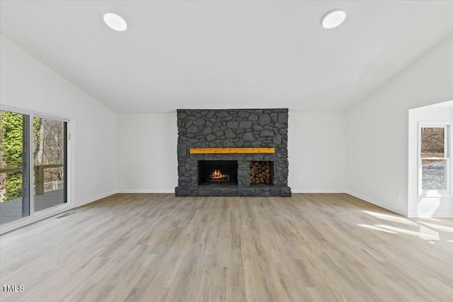 unfurnished living room featuring vaulted ceiling, a fireplace, and light hardwood / wood-style floors