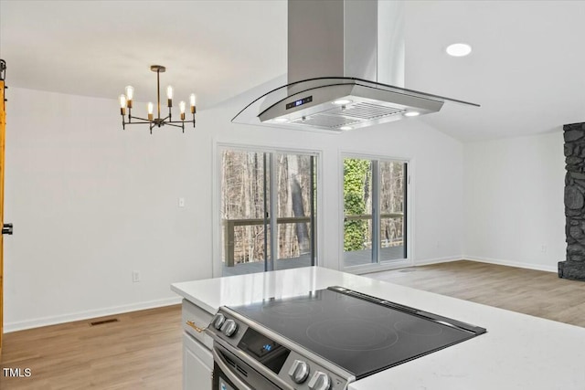 kitchen featuring stainless steel range with electric stovetop, island range hood, a notable chandelier, pendant lighting, and light hardwood / wood-style floors