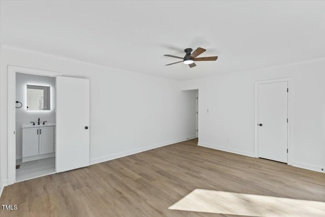 empty room featuring ceiling fan, sink, and light wood-type flooring