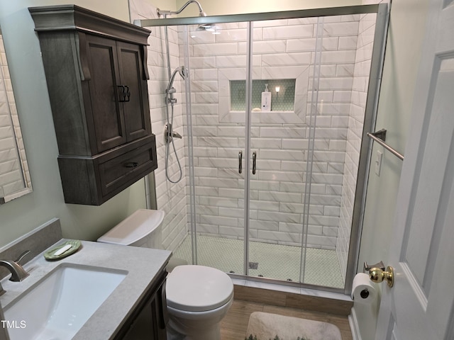 bathroom with vanity, hardwood / wood-style flooring, toilet, and walk in shower