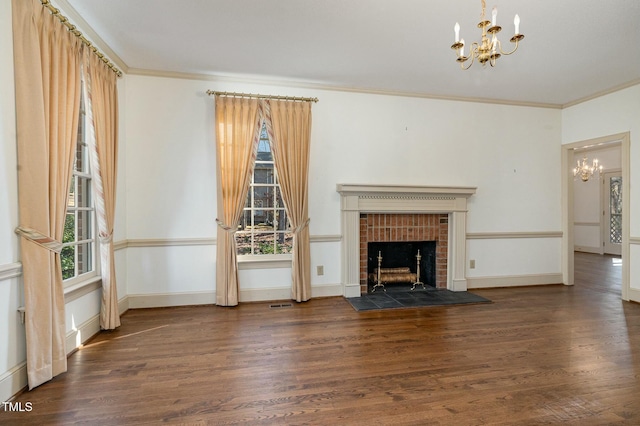 unfurnished living room featuring crown molding, dark hardwood / wood-style floors, a chandelier, and a brick fireplace