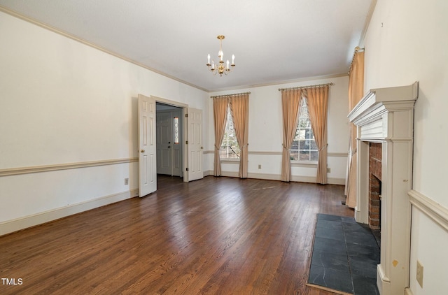 spare room with dark hardwood / wood-style flooring, a brick fireplace, crown molding, and a chandelier