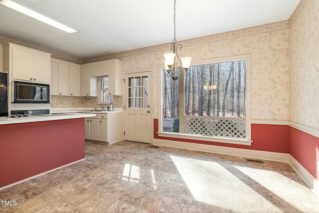 kitchen with hanging light fixtures, a notable chandelier, black microwave, and a healthy amount of sunlight