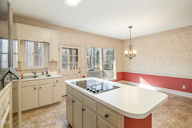 kitchen featuring sink, a center island, pendant lighting, black electric stovetop, and cream cabinetry