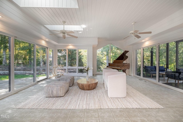 sunroom / solarium with ceiling fan, plenty of natural light, wood ceiling, and a skylight