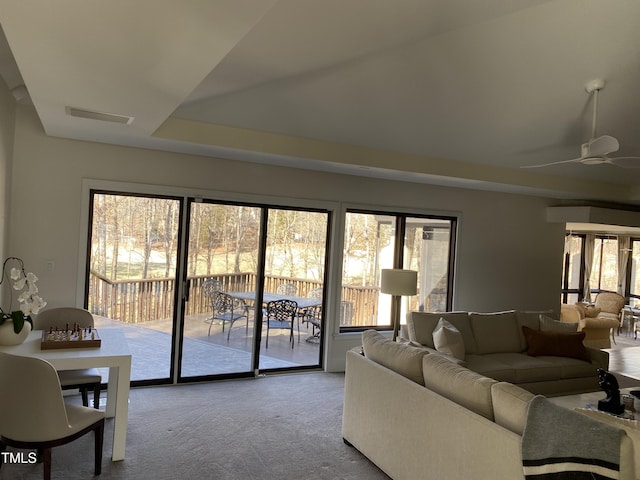 living room featuring a raised ceiling, carpet flooring, and ceiling fan