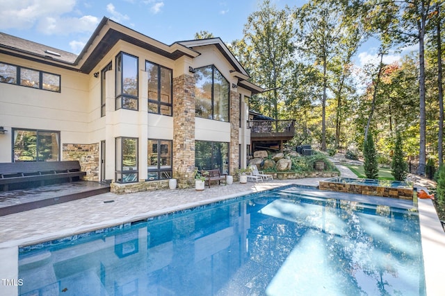 rear view of house with a swimming pool with hot tub and a patio area