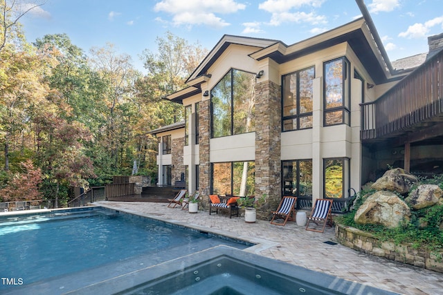 back of property with a pool with hot tub and a patio area