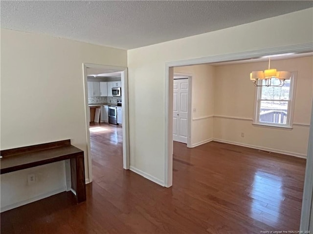 empty room with dark hardwood / wood-style flooring and a textured ceiling