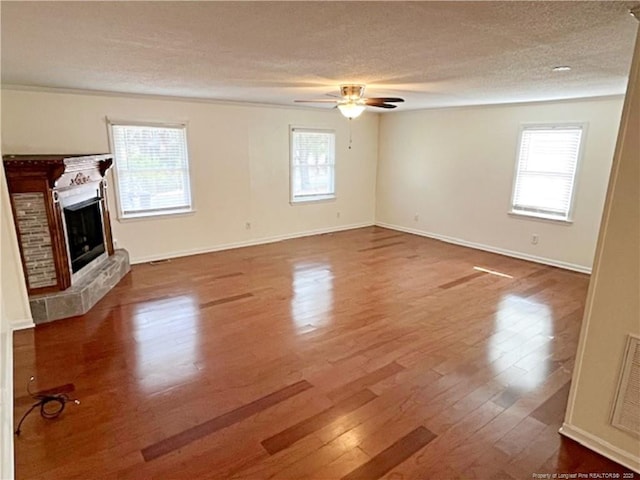 unfurnished living room featuring wood-type flooring, plenty of natural light, ceiling fan, and a textured ceiling