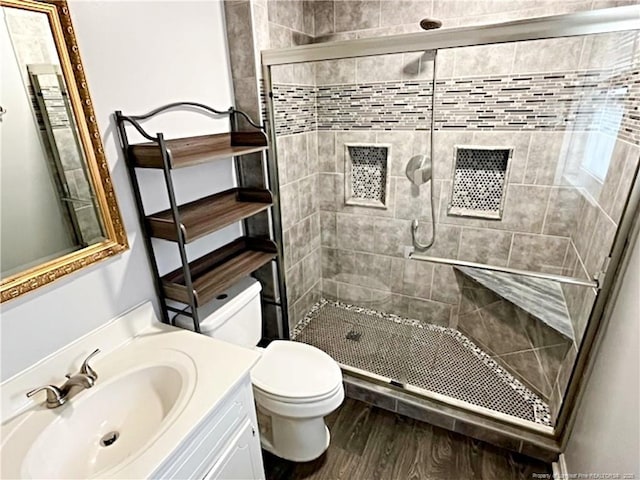 bathroom featuring wood-type flooring, vanity, an enclosed shower, and toilet