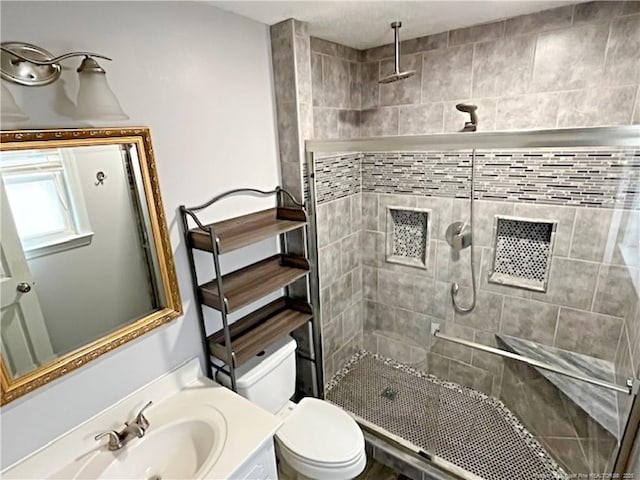 bathroom featuring vanity, toilet, and a tile shower