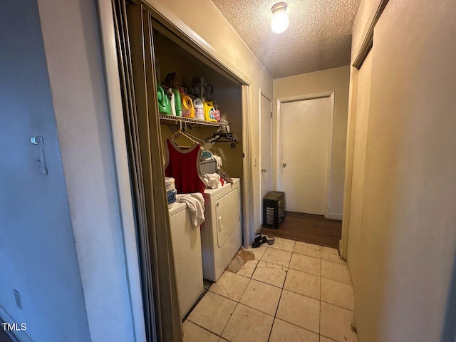 washroom featuring separate washer and dryer, a textured ceiling, and light tile patterned floors