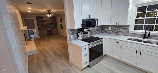 kitchen featuring stainless steel appliances, sink, white cabinets, and light hardwood / wood-style floors