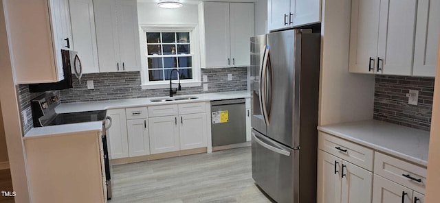 kitchen featuring white cabinets, dishwasher, sink, and stainless steel fridge