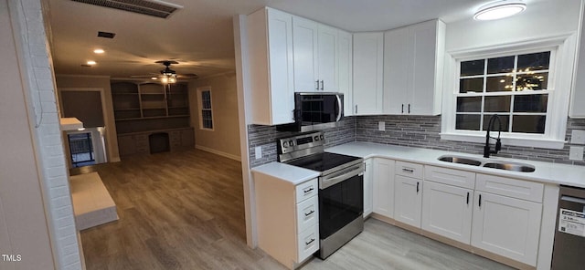 kitchen with sink, white cabinetry, light hardwood / wood-style flooring, appliances with stainless steel finishes, and decorative backsplash