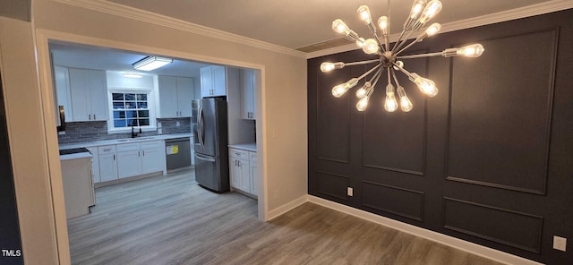 kitchen featuring crown molding, a chandelier, stainless steel fridge, dishwasher, and white cabinets